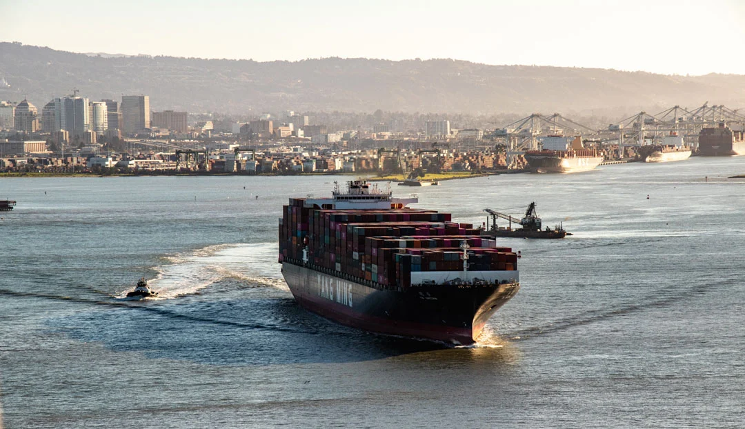 Ship sailing on the sea with a cityscape in the background.